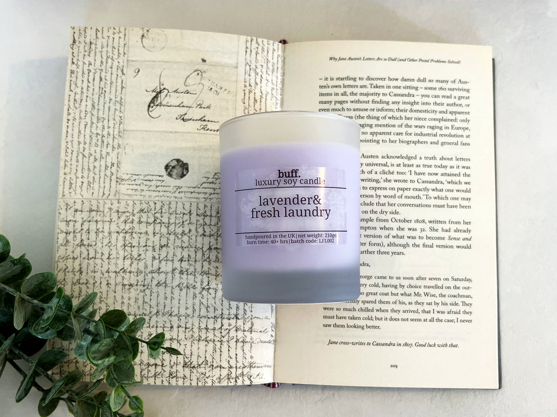 Lavender purple candle laying on an open book with surrounding leaves