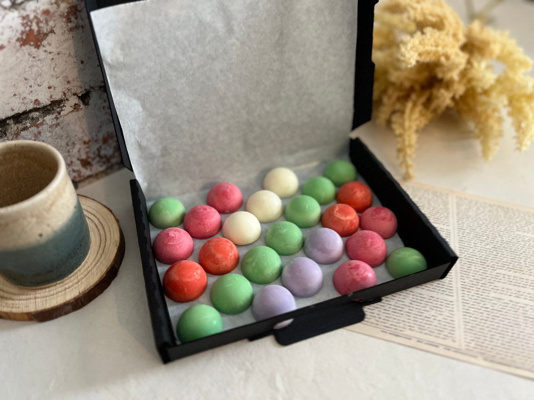 small dome wax melts in various colours inside a black gift box