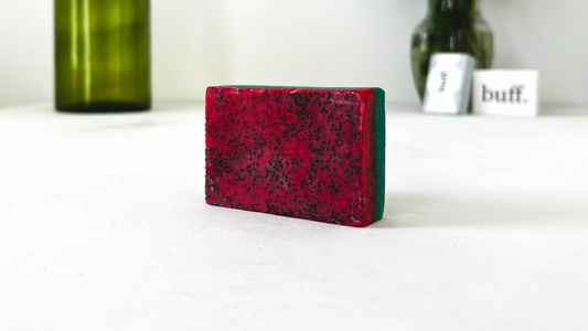 red and green soap bar infused with poppy seeds on a white table