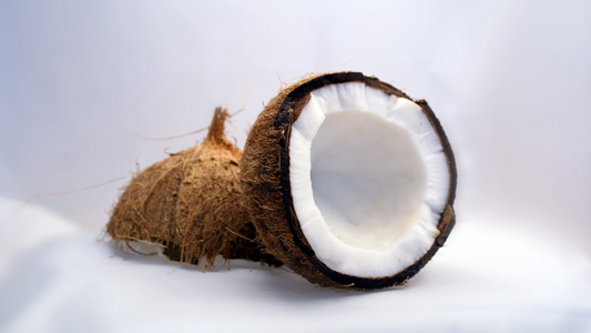 a coconut cut open lays on a white table