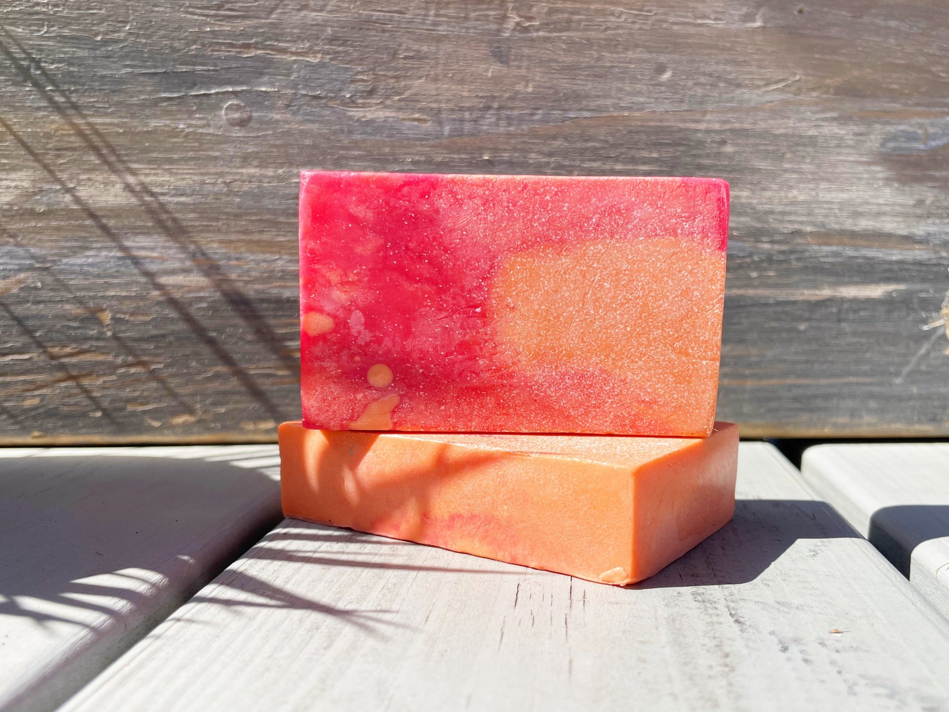 A red and orange rectangle bar soap, placed on a wooden surface.