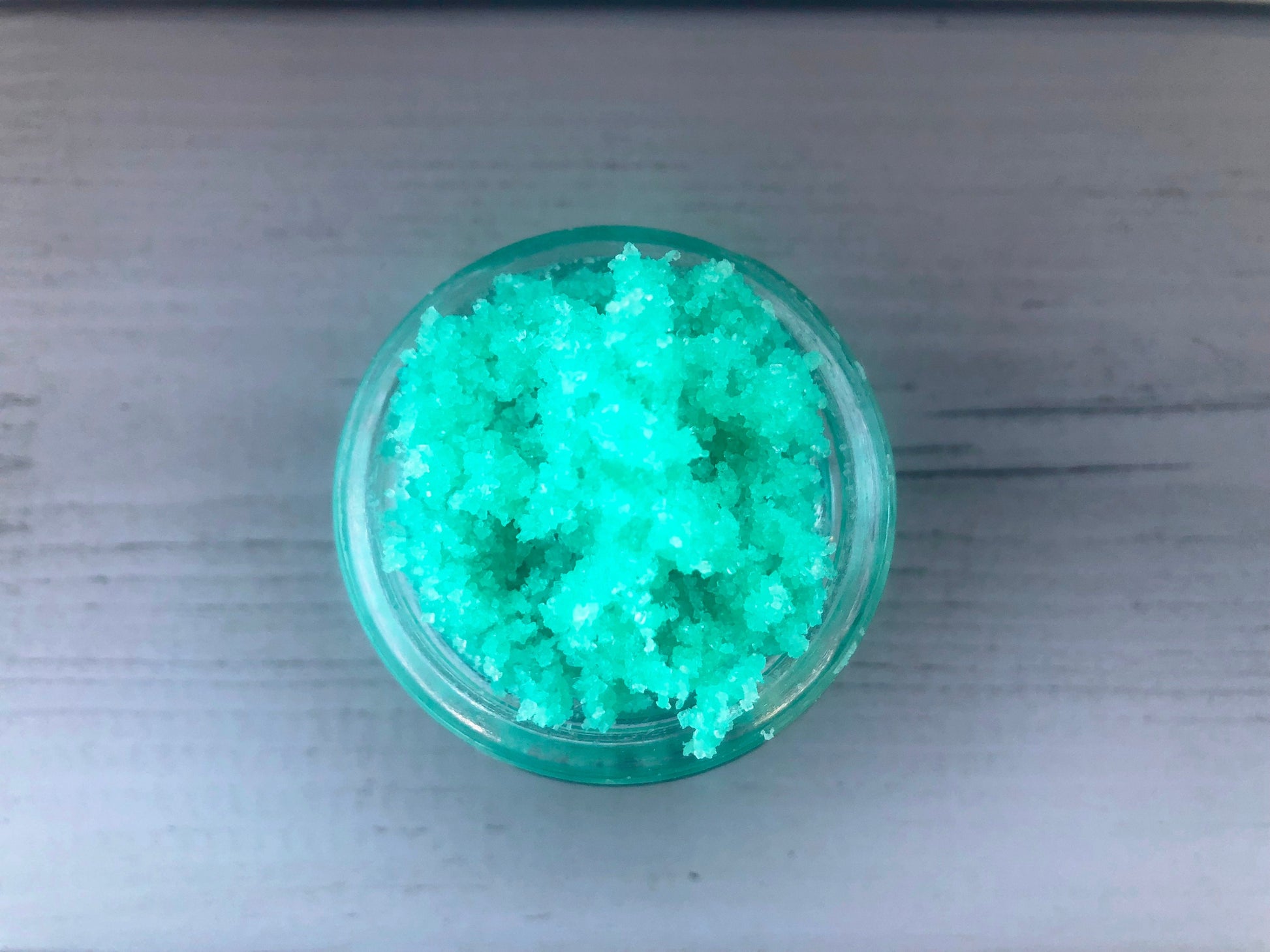 Green watermelon sugar lip scrub used for exfoliating in a glass jar