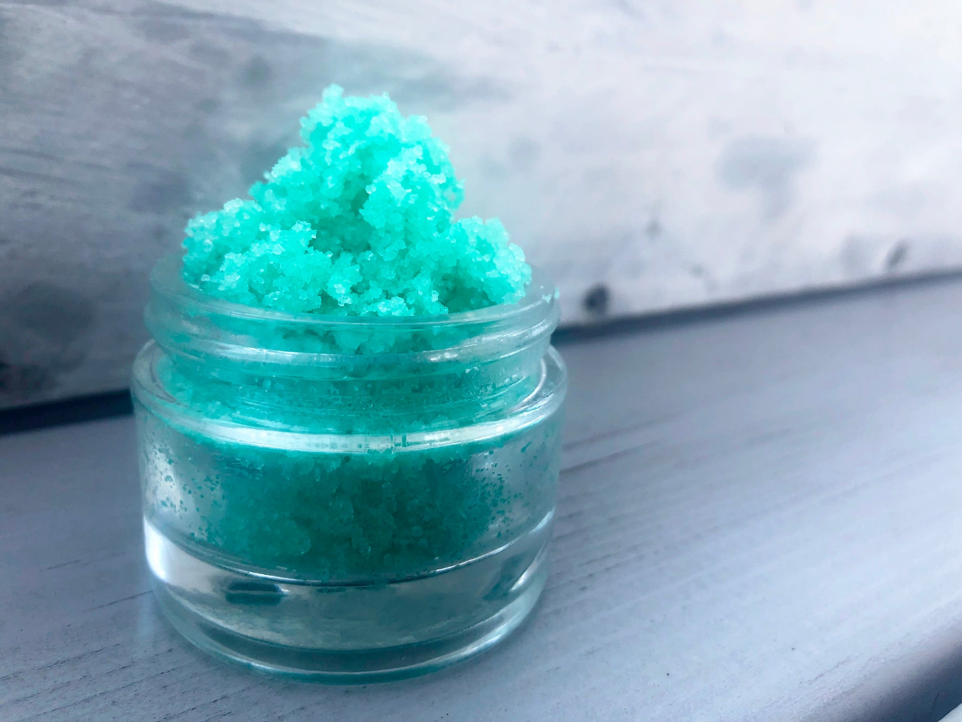 Green watermelon sugar lip scrub used for exfoliating in a glass jar