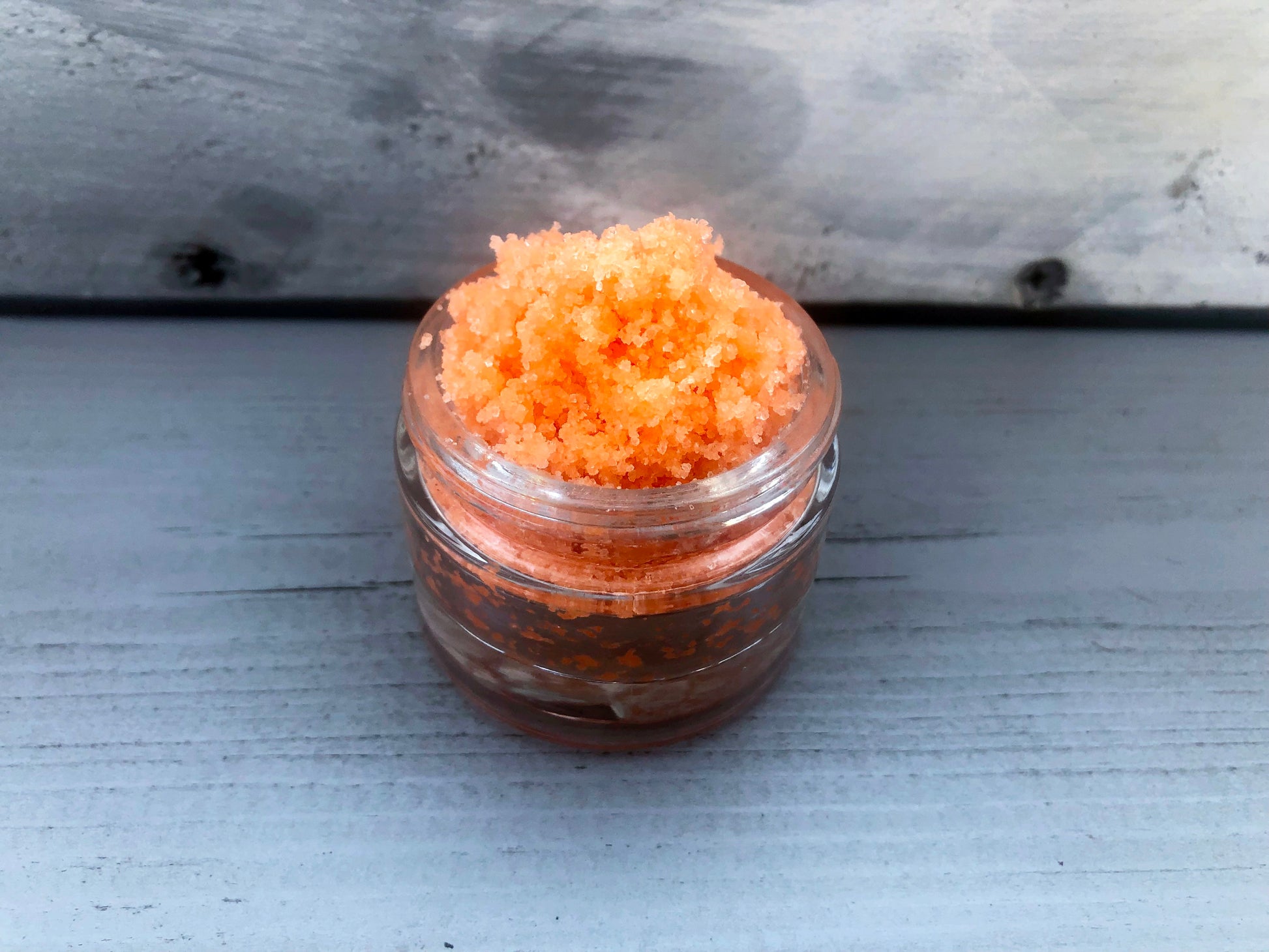 Orange Tutti Fruity sugar lip scrub used for exfoliating in a glass jar
