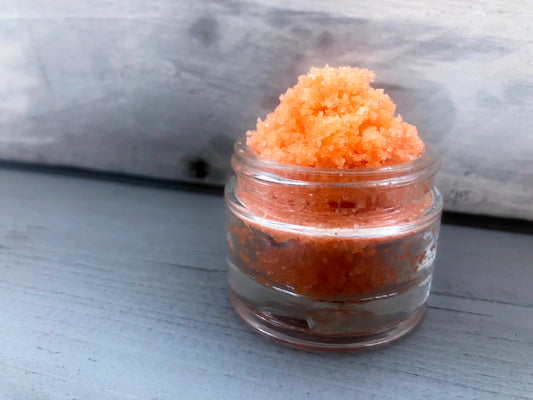 Orange sugar lip scrub used for exfoliating in a glass jar