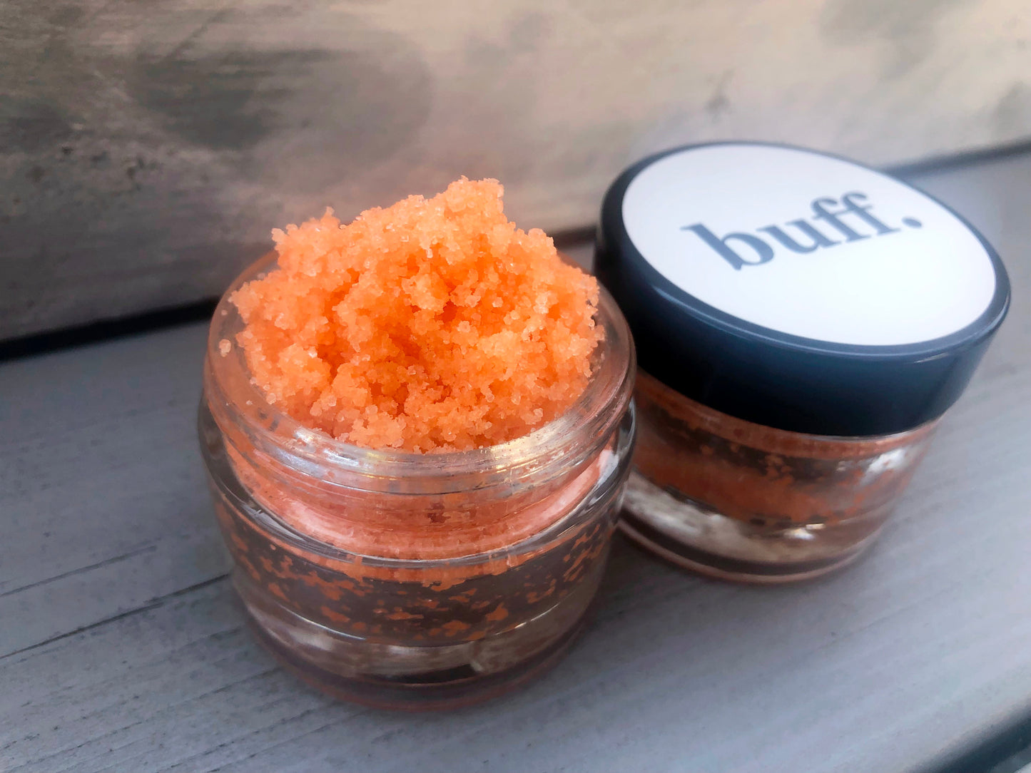 Orange Tutti Fruity sugar lip scrub used for exfoliating in a glass jar