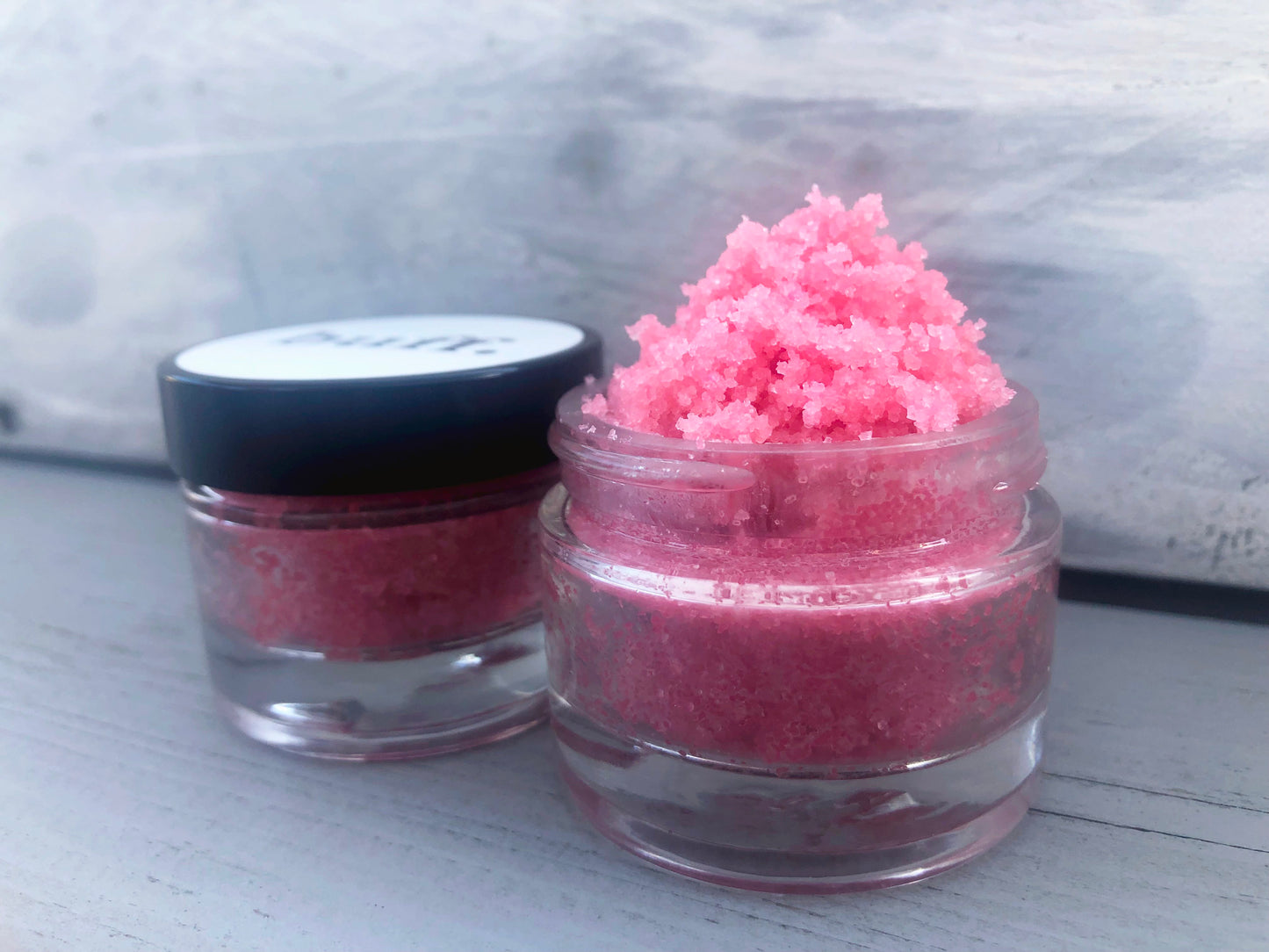 Pink strawberry sugar lip scrub used for exfoliating in a glass jar